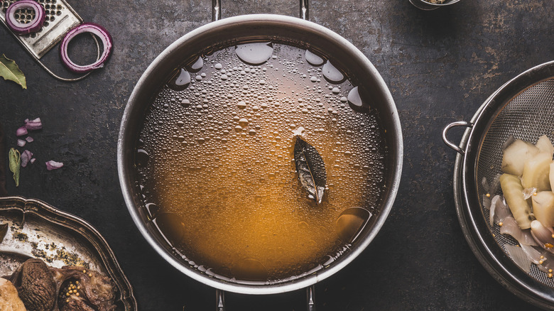 A pan of homemade vegetable stock with a bay leaf floating in it