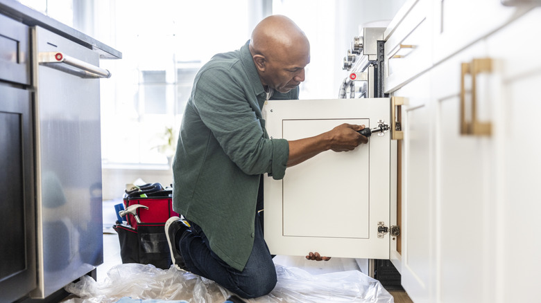 Man adjusting kitchen cabinets