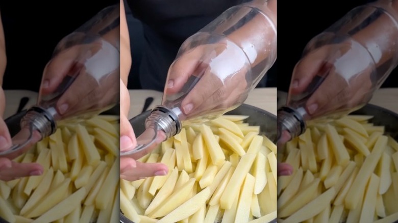 Person cooking fries with plastic bottle over their hand