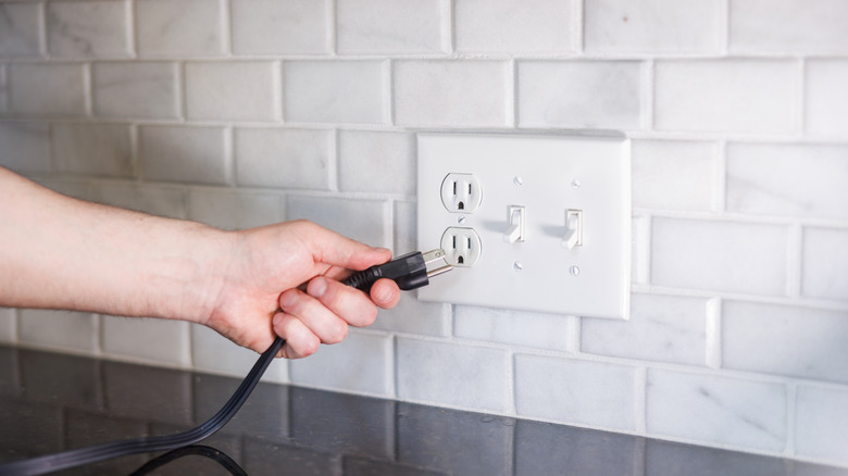 Hand plugging in cord to outlet
