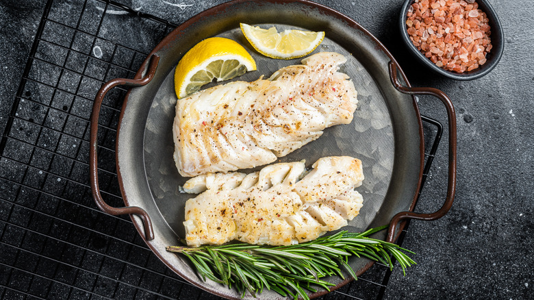 Roasted cod on a plate surrounded by garnishes.