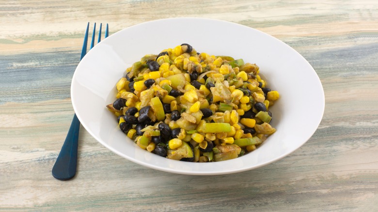 Zucchini, corn, and beans in a white bowl
