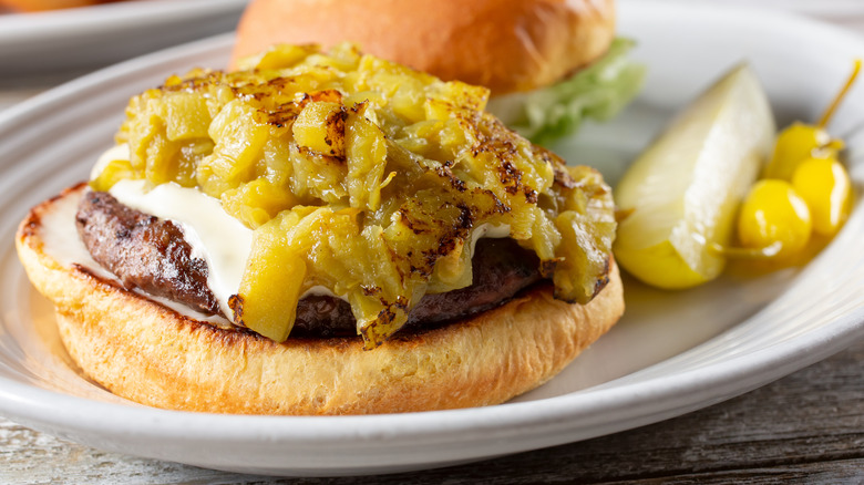 Green chile open-faced cheeseburger with pickles on plate