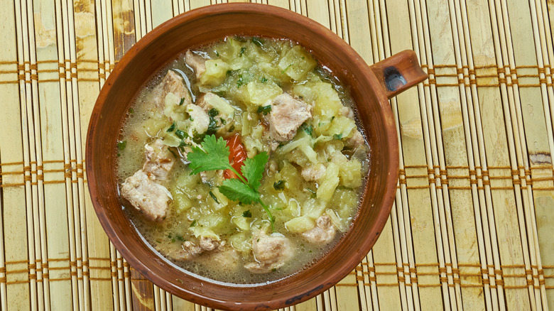 Green chile stew close-up in brown bowl