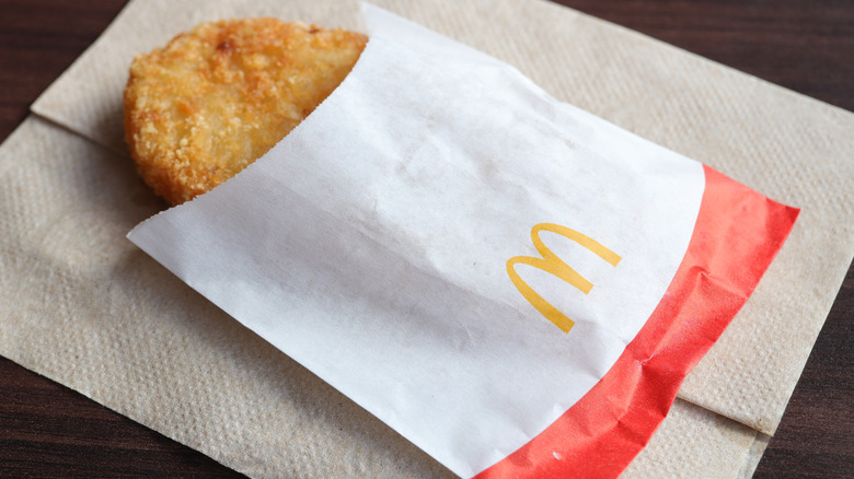 A McDonalds hash brown in a wrapper on a napkin.