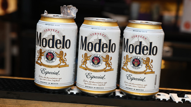 Three cans of Modelo on a bar top