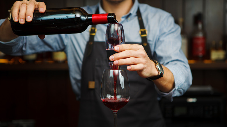 Pouring red wine through handheld aerator