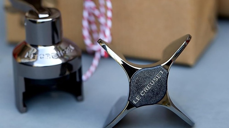 Two Le Creuset champagne stoppers with gift box in background