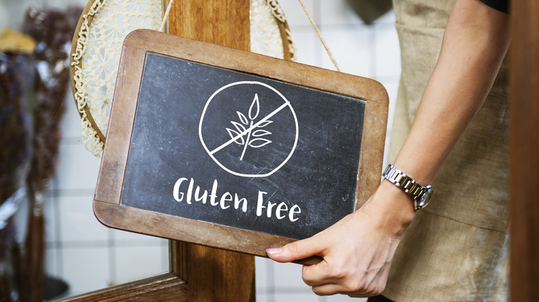 A woman hanging a "Gluten Free" sign on the door