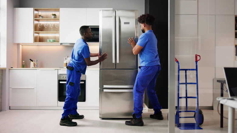People installing a fridge in the kitchen
