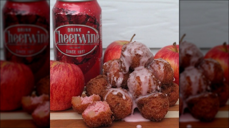 pile of candied apple hush puppies with Cheerwine glaze beside a can of Cheerwine
