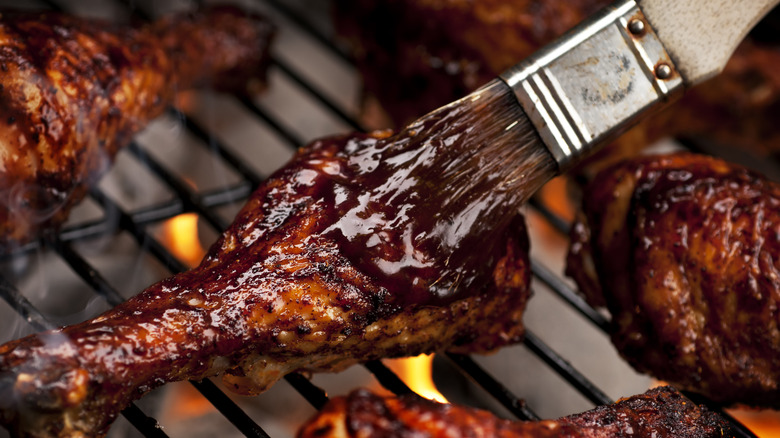 barbeque sauce being spread on grilling wings