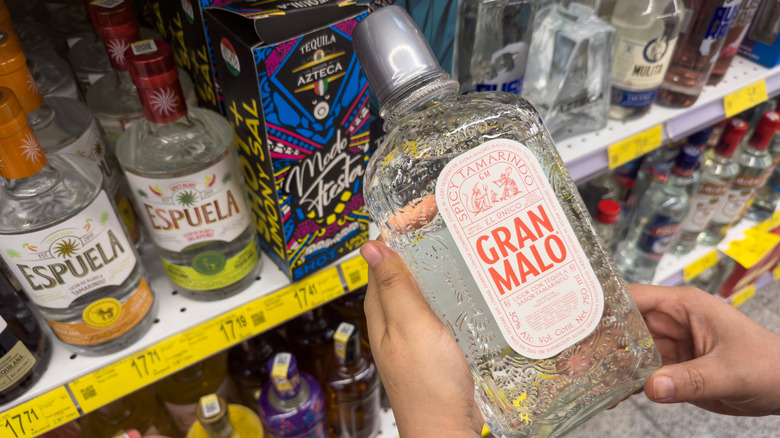 a hand holding a bottle of tequila