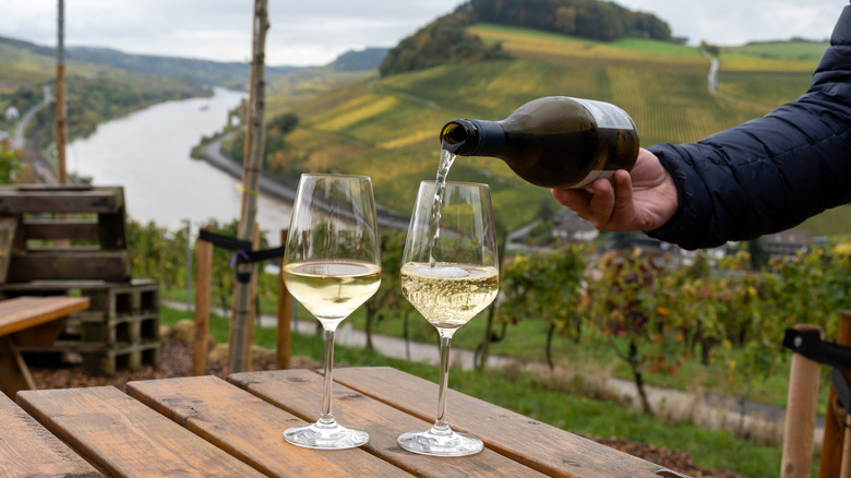 Hand pouring riesling into two wine glasses
