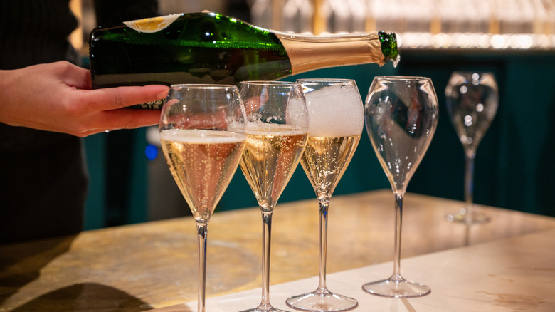 Hand pouring Champagne into glasses