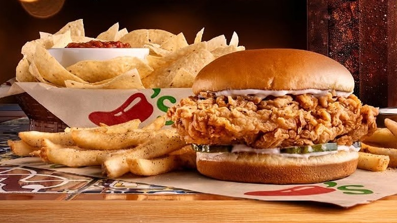 Chili's chips and salsa, fried chicken sandwich, and french fries on table
