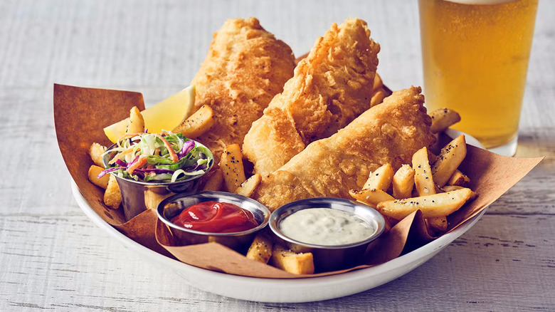 Promo for Bonefish Grill fried fish with fries, slaw, and tartar sauce in a paper-lined bowl next to a beer