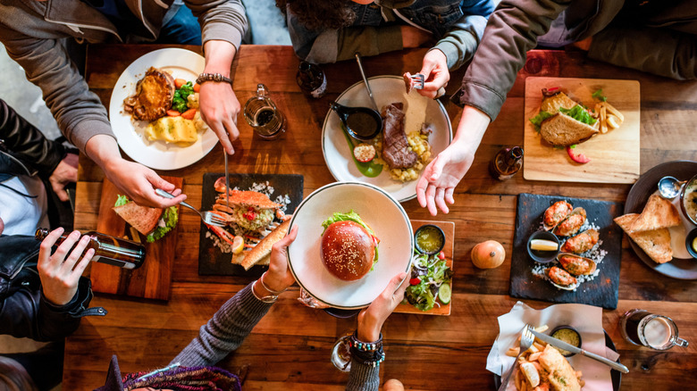 Aerial view of diners passing food on a wooden table