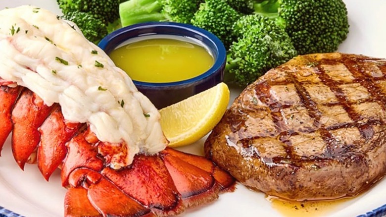 Red Lobster sirloin steak and lobster tail on white plate with broccoli, lemon, and butter