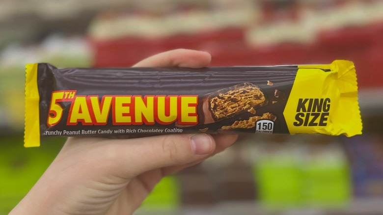 A hand holds a wrapped 5th Avenue Candy Bar