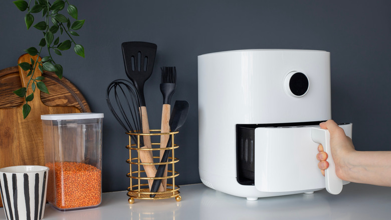 hand pulling out bottom drawer of air fryer