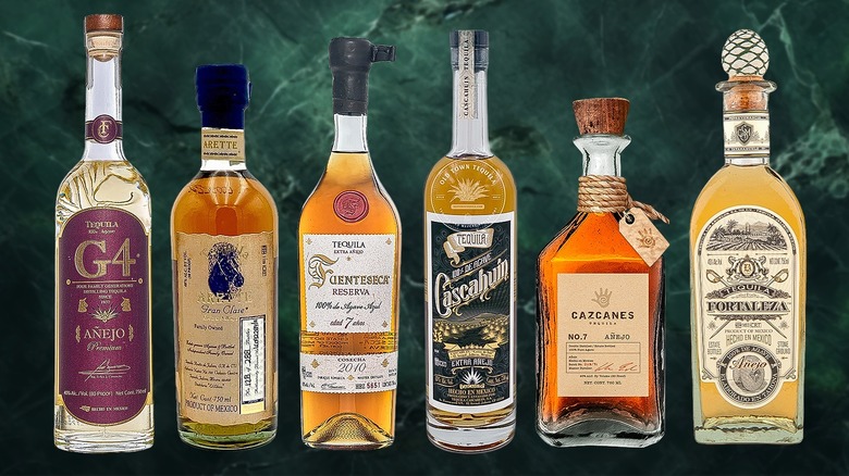 Six bottles of añejo tequilas against a green marble background