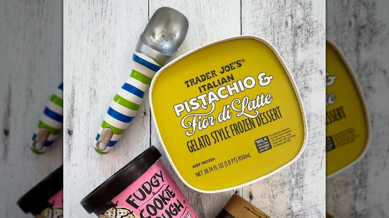 Trader Joe's Italian Pistachio & Fior di Latte Gelato Style Frozen Dessert and a striped ice cream scoop on a white wooden table