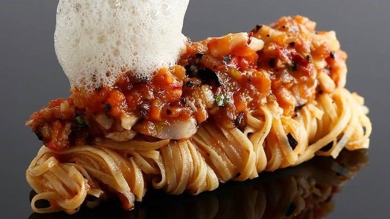 Lobster bolognese with a dollop of foam being dropped on top