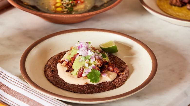 A taco plated on a cream colored plate with brown rim