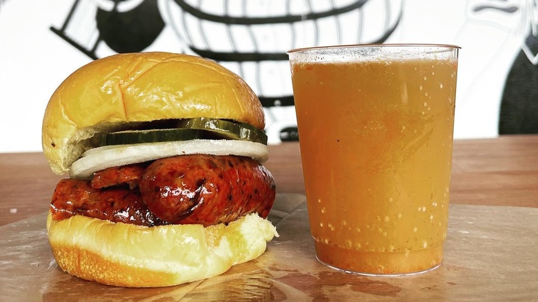 A house-made sausage sandwich with a mimosachelada