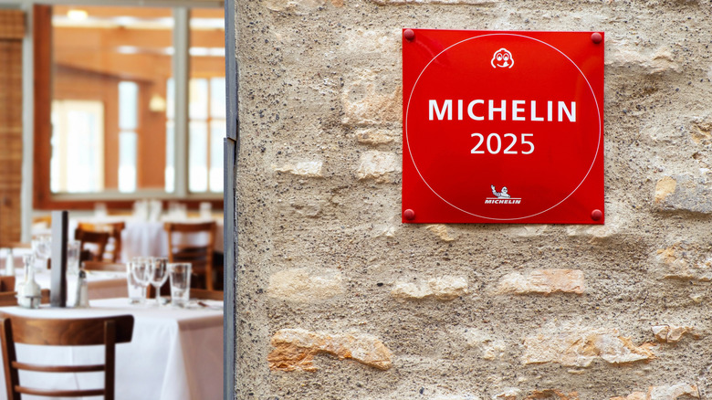 A red Michelin 2025 plaque on a stone wall beside the door to a restaurant