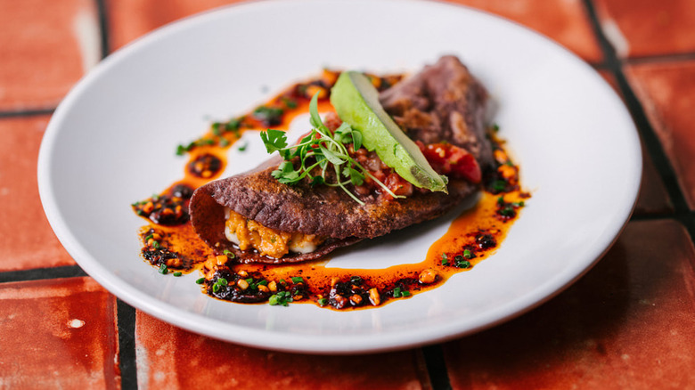 Taco plated with elegant circle of deep red sauce