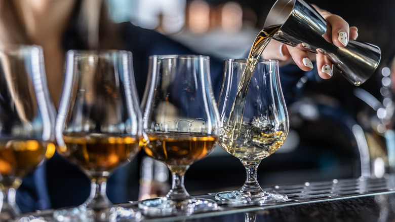 bartender pouring whisky into glasses