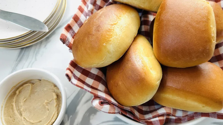 A basket of dinner rolls with a ramekin of compound butter