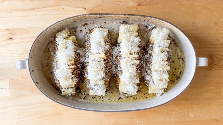 A casserole dish of Hasselback potatoes topped with cheese