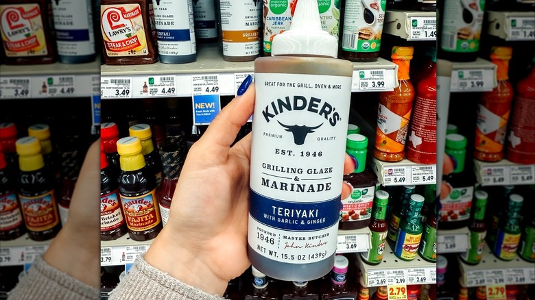 A woman holding a bottle of Kinder's teriyaki marinade