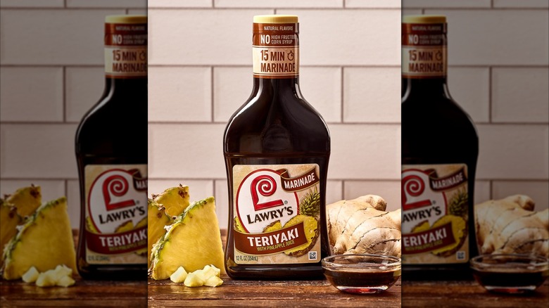 A bottle of Lawry's teriyaki marinade on a wooden counter with ginger and pineapple