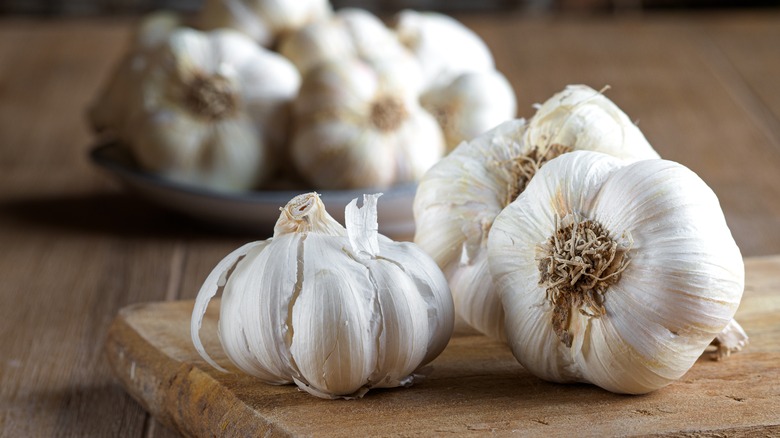 Whole garlic cloves with wooden board