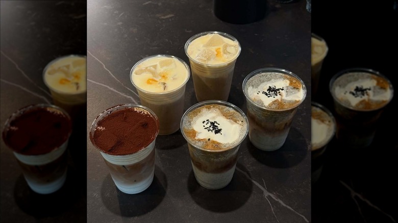 Five coffee drinks in takeout cups with various toppings