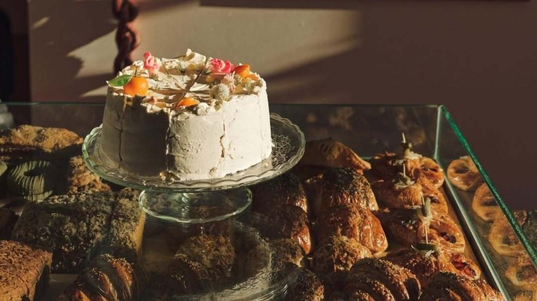 A frosted cake on top of a display case full of pastries