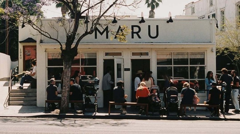 The white exterior of Maru coffee with people sitting outside