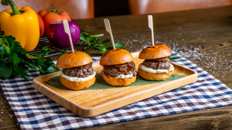 Three sliders are arranged on a wooden board.