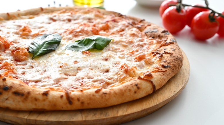 A pizza on a wooden board on a white table