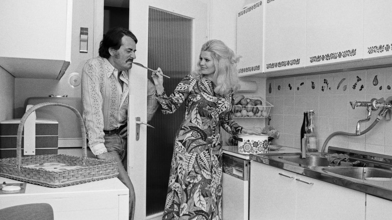 Black and white photo of a couple in the kitchen in the 1970s
