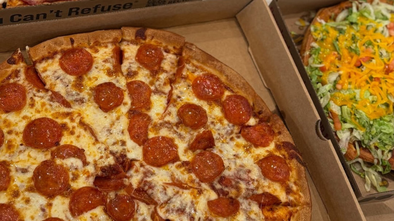 Boxes of pizza from Godfather's pizza sitting side by side. The one on the left is pepperoni and taco pie is on the right.