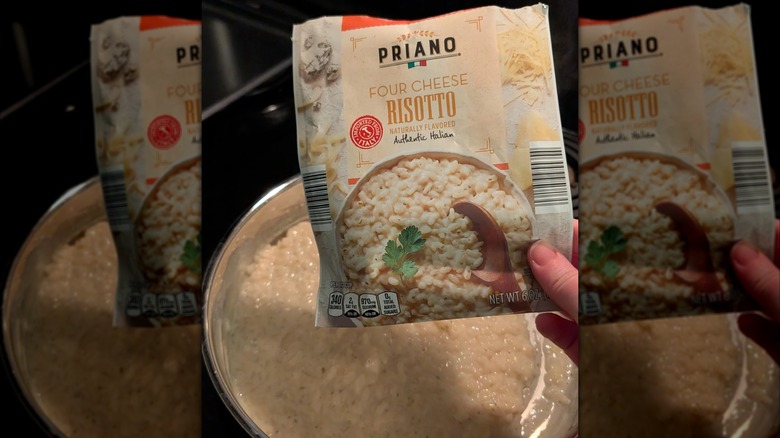 Hand holding a Priano Four Cheese Risotto packet over risotto in a pot on the stove