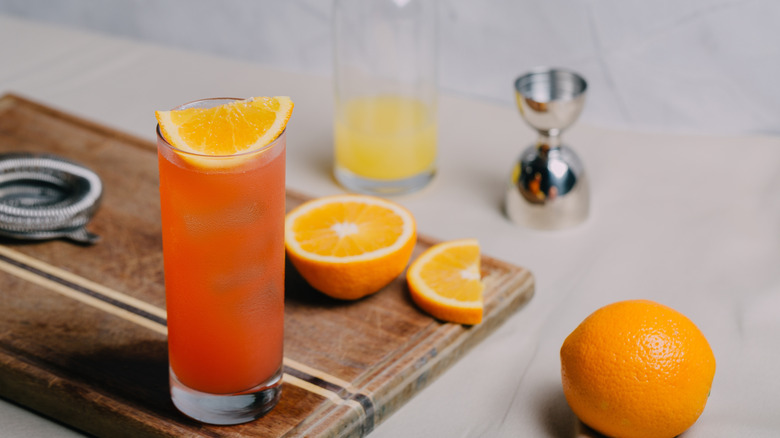 Garibaldi cocktail with some ingredients and cocktail shaker parts