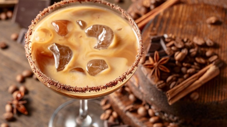 A whisky and cream cocktail served in a stemmed glass over ice with a spice rim.