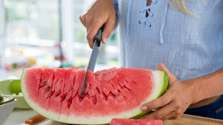 Mid-section of woman cutting fruits on chopping board against white background
