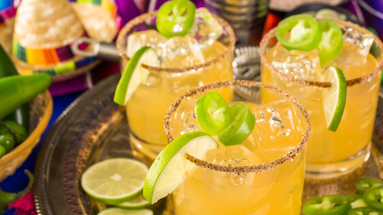 Spicy grapefruit palomas with jalapeño and lime slices as garnish and a spiced, salted rim
